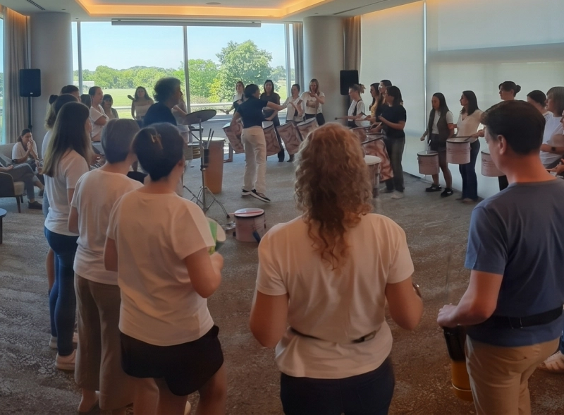 Facilitador guiando un círculo de percusión dinámico con participantes de una empresa en Buenos Aires.