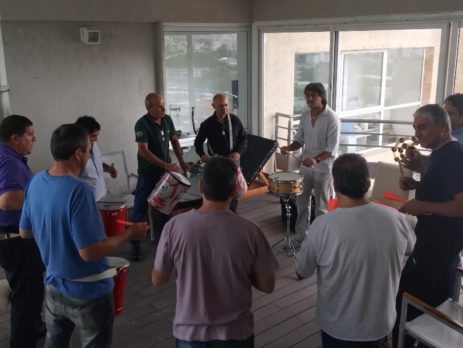 Empleados y líderes colaborando en un círculo de percusión, descubriendo cómo mejorar el clima laboral en una empresa en Argentina.